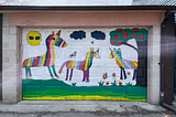 Colourful garage door in one of Toronto’s laneways features a painting of 3 rainbow horses lounging on a field with a sun wearing sunglasses.