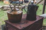 Image of a metallic jar and metallic kettle on a stove.