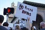 Protest sign reads “No forced births”