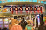 A photo in Las Vegas McCarran airport with its bright, neon Welcome to Las Vegas sign, slot machines and people walking