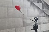 Banksy’s ‘Girl with Balloon’. A red heart-shaped balloon blowing away from a forlorn little girl.