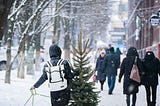 Someone takes home a Christmas tree in the snow in the city.