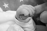 Close up of baby holding mother’s finger.