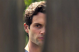 A Creepy guy staring through a fence. Penn Badgley.