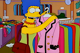 Marge Simpson holding up a pink suit in a store.
