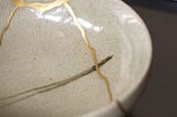 Close up of gold paint along the cracks of a bowl as an example of kintsugi.