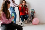 Young girls on a scooter blowing bubbles
