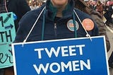 Woman holding a blue sign with “TWEET WOMEN WITH RESPECT” in white lettering