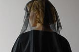 Picture of a woman dressed in black funeral style clothing.