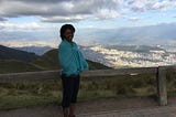 Aneisha standing in front of a mountain in Ecuador wearing a blue shawl.