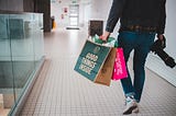 A man walks through a mall holding shopping bags