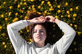 Woman daydreaming while lying in a field of yellow flowers