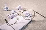 Eyeglasses near crumpled paper