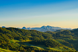 Photo of a green mountain range against a blue, cloudless sky.