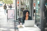 A Woman Sitting Outside a Cafe Working on Her Computer