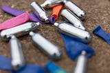 Several nitrous oxide canisters and balloons on the ground