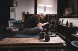 A master Japanese potter makes clay cups at his wheel.
