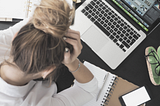 Young woman frustrated in front of a laptop computer. Holding her head in her hands