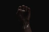 A black folded fist with BLM written on the wrist
