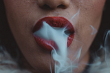 Ladies mouth with red lipstick smoking.