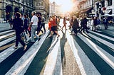 a crowd of people crossing the street in a big city