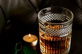 A glass of whisky and a lit candle