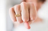 Photo of a fist wearing a ring that says, “I am badass.”
