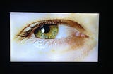 An eye with green iris: Medium is watching you, and wants you to gain 100 followers.