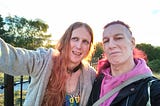two people outside in the sun, smiling for a selfie
