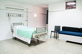 A typical hospital bed, with IV stand next to it.