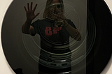 A selfie of me taken in the reflection of a dryer door. I’m trying to recreate the classic Boy Behind Glass stock image for autism