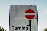 Street sign indicating that the route ahead is blocked and vehicles must take a turn.
