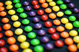 Rows of Skittles candy arranged by color on a black background.
