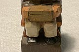Carved statue of an older man holding a box while sitting