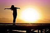 image of woman on beach greeting the sun