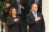 Vice-President Kamala Harris stands next to her husband, Second Gentleman Doug Emhoff, with their hands over their hearts, pledging allegiance to the flag.