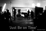 A black and white, backlit image of a film set with “Just Be on Time”, a quote attributed to Alexander Payne, at the bottom of the image in the foreground.