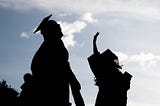 Graduates in silhouette celebrate outdoors.