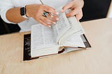 Woman holding pen reading book