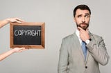 Partial view of a woman holding a chalkboard with copyright inscription next to a thoughtful businessman.