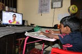 A kid looks at the TV playing a video lesson on the KITE VICTERS channel