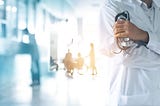 A doctor standing, holding his stethoscope