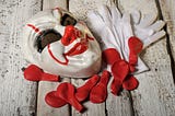 Clowns mask with white gloves and red balloons on wooden boards