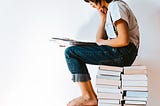 boy sitting on stack of books