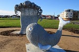 Woven wire sculpture of fish and pouncing wave