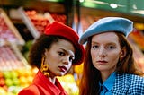 two girls, one wears a red beret and the other a blue one