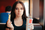 Hesitating woman thinking about eating fast food or not