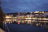 Early evening on the riverfront in Zurich, Switzerland with the lights from the town reflecting in the water.