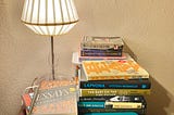 A photo of books stacked on my bedside table