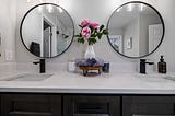 White bathroom sink with double black taps and mirrors